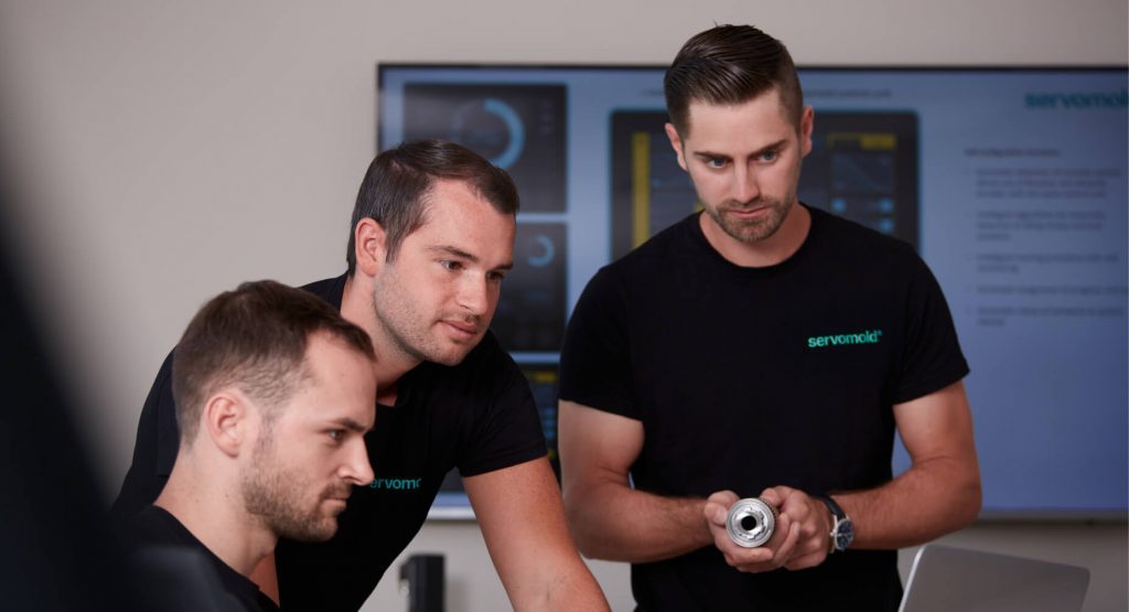 Drei Mitarbeiter in Schwarzem T-Shirt betrachten Bildschirm